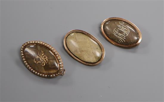 A George III yellow metal and plaited hair mourning brooch with inscription and two other similar mourning brooches,